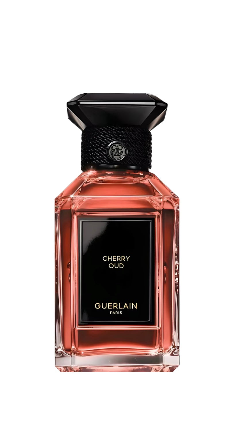 Guerlain Cherry Oud perfume bottle with pink liquid, a black label and black cap on a white background.